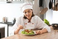 Young female chef preparing tasty salad in kitchen Royalty Free Stock Photo