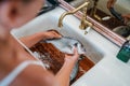 Young female cleaning the fresh orata or dorada fish after the gutting under the kitchen sink water tap. Healthy fresh seafood Royalty Free Stock Photo