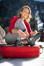 Young female climber putting climbing shoes on before climbing on a boulder outdoors