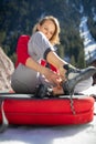 Young female climber putting climbing shoes on before climbing on a boulder outdoors