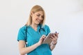 Young female clinician doctor in scrubs using touchpad while communicating with patients online. Portrait Of Smiling Female Doctor Royalty Free Stock Photo