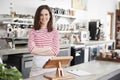 Young female coffee shop owner behind counter, arms crossed Royalty Free Stock Photo