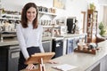 Young female coffee shop owner behind the counter, smiling Royalty Free Stock Photo