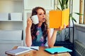 young female college student with book and cup of coffee studying at home reading homework Royalty Free Stock Photo