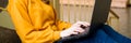 Young female college student sitting on stairs at school, writing essay on her laptop. Education.