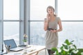 Young female consultant having business call in office at her workplace. Secretary speaking on the smart phone, holding