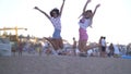 Young Female Couple jump On Beach in the evening, Two Girls have fun Seaside, hands up Royalty Free Stock Photo