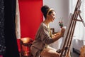 Young female creative pretty african american artist paints picture with oil paints in art studio Royalty Free Stock Photo