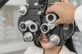 Young female customer being examined visual test using Bifocal Optometry eyesight measurement device by ophthalmologist in optical