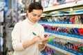 Young female customer choosing different pens in stationery shop