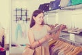 Young female customer selecting shoes in footgear center