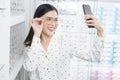 Young female customer trying on glasses and taking a selfie in optical center, Eyecare concept