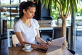 Young female with cute smile sitting with portable net-book in modern coffee shop interior during recreation time, charming happy Royalty Free Stock Photo