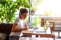 Young female with cute smile sitting with portable net-book in modern coffee shop interior during recreation time, charming happy Royalty Free Stock Photo