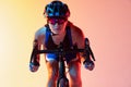 Close-up female cyclist riding a bicycle isolated against neon background Royalty Free Stock Photo