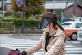Young female cyclist wearing protective face mask and sun visor on busy Japanese street