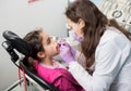 Young female dentist is checking up patient girl teeth at dental office