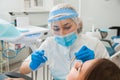 Young female dentist curing patient`s teeth filling cavity