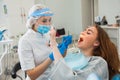 Young female dentist curing patient`s teeth filling cavity