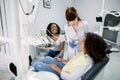 Young female dentist with dental drill, making dental treatment of her little patient African American girl. Young Royalty Free Stock Photo