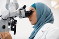 Female Dentist Doctor In Hijab Working With Modern Dental Microscope In Clinic