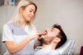 Young female dentist examining male patient`s teeth in a dental clinic