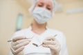 Young female dentist with mirror and periodontal explorer in clinic, closeup, focus on dental instruments