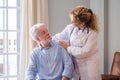 Young female doctor encouraging senior man at home. Doctor helping senior patient and giving care. Female homecaregiver taking Royalty Free Stock Photo