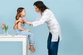 Young female doctor examining little girl with a stethoscope. Side view Royalty Free Stock Photo