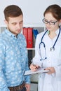 Young female doctor in glasses explaining diagnosis to her male patient. Healthcare or insurance concept. Royalty Free Stock Photo