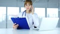 Young Female Doctor Holding Medical Reports, Talking on Phone Royalty Free Stock Photo