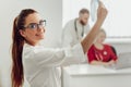 Young female doctor in hospital looking at x-ray. The other two doctors communicate in the background. Royalty Free Stock Photo