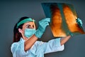 Young female doctor looking at the x-ray picture  on grey background Royalty Free Stock Photo