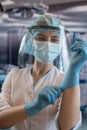 Young female doctor or nurse assistant surgeon putting on gloves standing in operation room Royalty Free Stock Photo