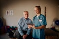 Young female doctor nurse in uniform and stethoscope holding digital tablet with senior patient Royalty Free Stock Photo