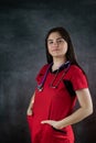 Young female doctor or nurse wear red uniform with stethoscope isolated on black Royalty Free Stock Photo