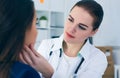 Young female doctor palpating lymph nodes of a patient. Medical exam, clinic.