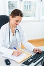 Doctor at desk in clinic writing a file or dossier