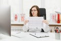 Young female doctor sitting at desk with medical documents, electrocardiogram record, heart ekg cardiogram chart of wave Royalty Free Stock Photo