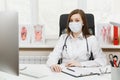 Young female doctor sitting at desk, working on modern computer with medical documents in light office in hospital Royalty Free Stock Photo