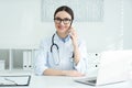 Female doctor talking on phone at table in office Royalty Free Stock Photo