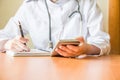 Young female doctor using modern smartphone in the hospital, seeking information in the internet.