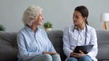 Young caregiver talk with positive elderly woman at home Royalty Free Stock Photo