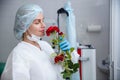 A young female doctor in a white protective suit, cap and gloves holds a red rose presented to her Royalty Free Stock Photo