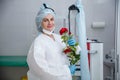 A young female doctor in a white protective suit, cap and gloves holds a red rose presented to her Royalty Free Stock Photo