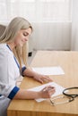 Young female doctor working desk in doctor`s room writing. Royalty Free Stock Photo