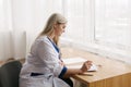 Young female doctor working desk in doctor`s room writing. Royalty Free Stock Photo