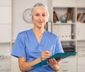 Positive young female doctor takes important notes while standing in a office Royalty Free Stock Photo