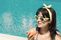 Young female drinking grapefruit juice next to the swimming pool Royalty Free Stock Photo