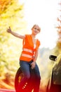 Young female driver wearing a high visibility vest, calling the roadside service Royalty Free Stock Photo